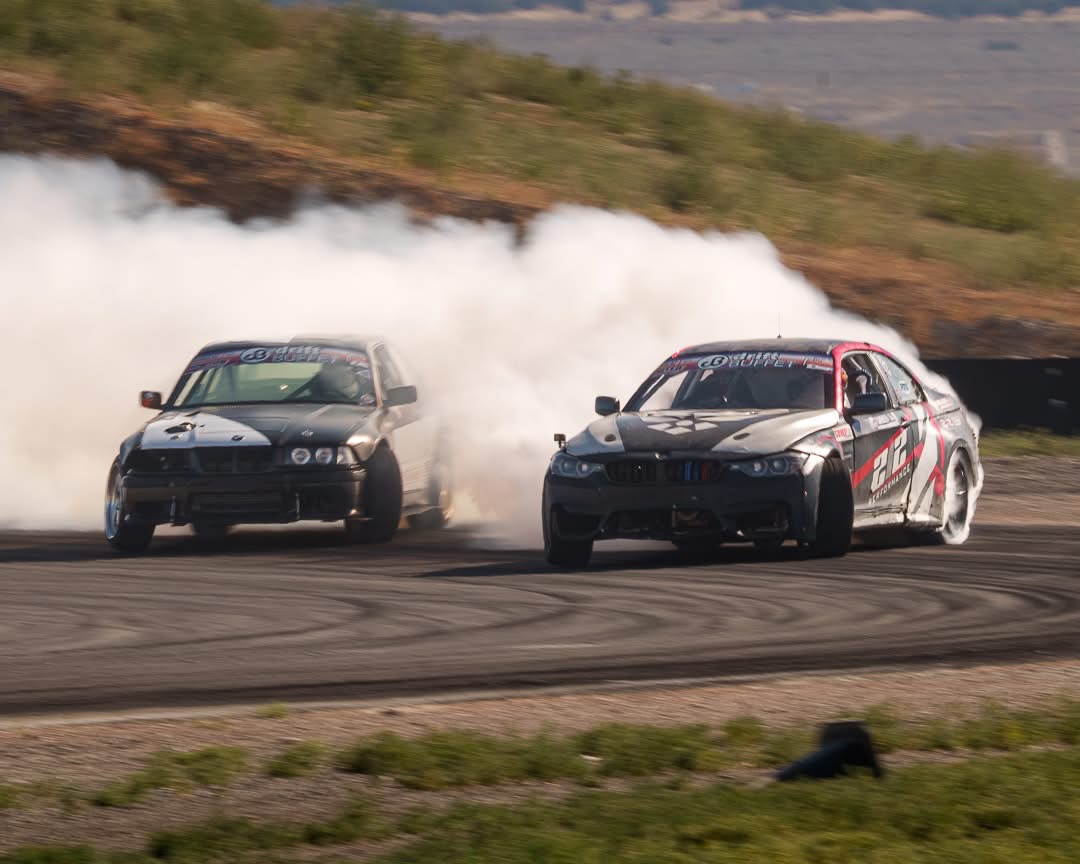 Two BMW drift cars in close tandem with massive tire smoke