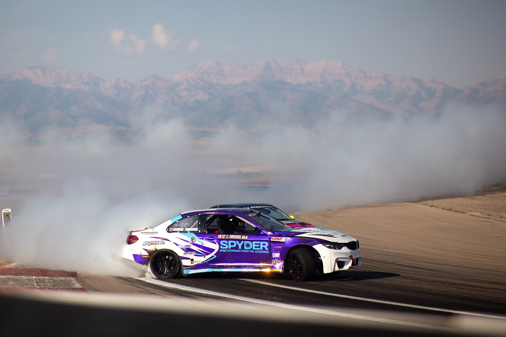 Spyder BMW M4 drifting solo with snowy mountain backdrop